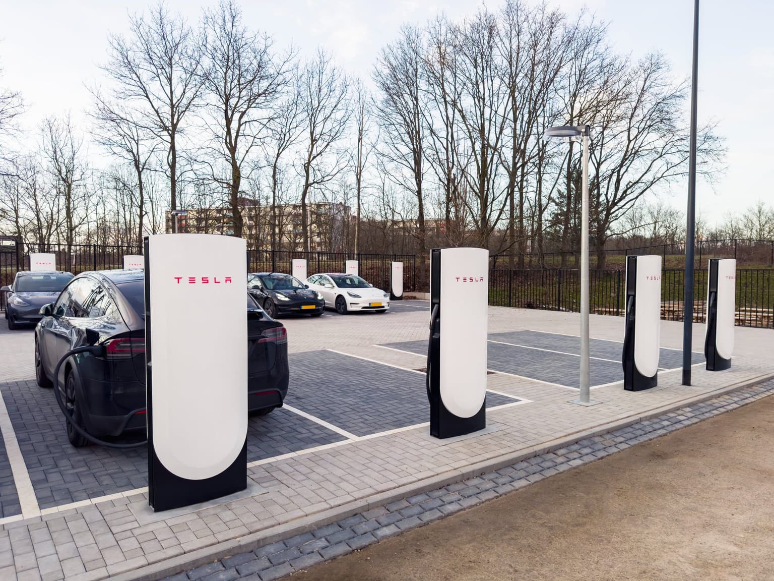 cars charging in a Tesla Supercharger car park