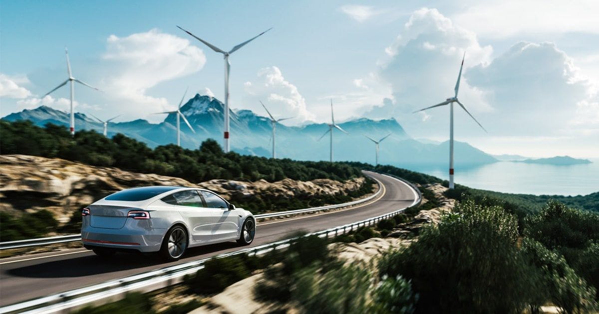 electric car driving down an open road with turbines
