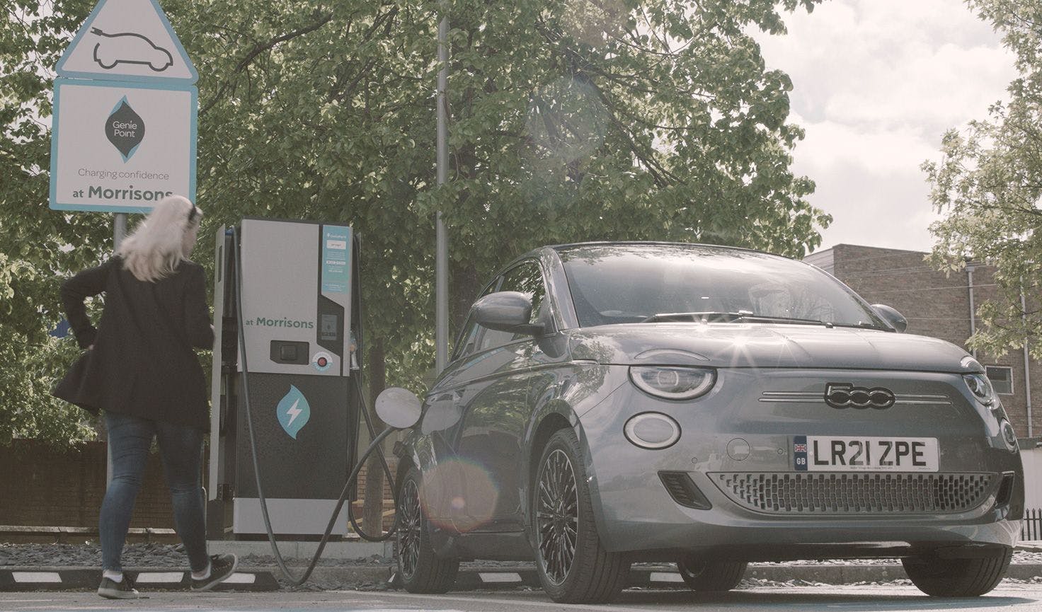 A woman returning to her ev after charging it using a public charge point