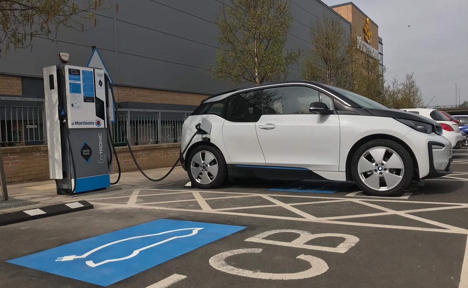 An electric vehicle plugged in to a charging spot outside a popular chain supermarket