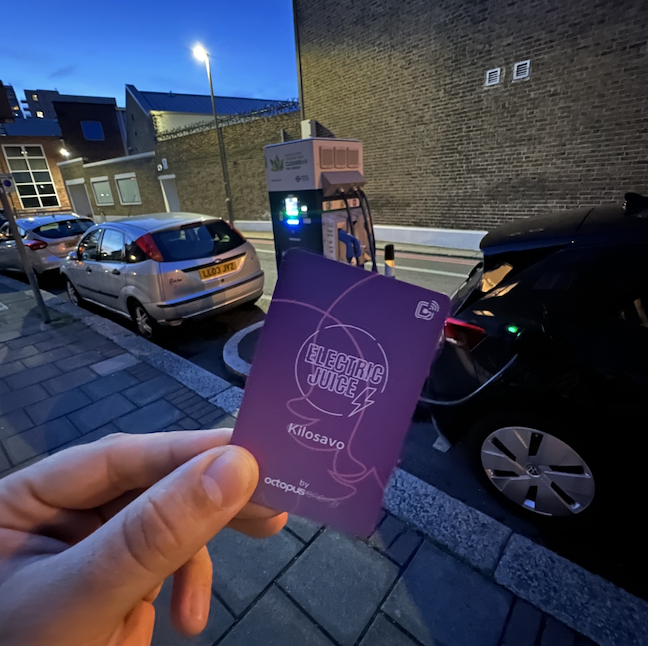 Image of the electric juice card next to an electric car that is charging at night